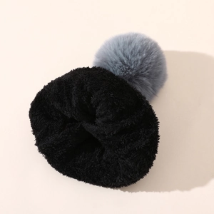Dettaglio di un cappello invernale spesso con pompon grigio e morbida texture in pile nero