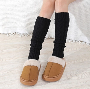 Close-up of thick cable knit leg warmers paired with winter fur-lined warm mules