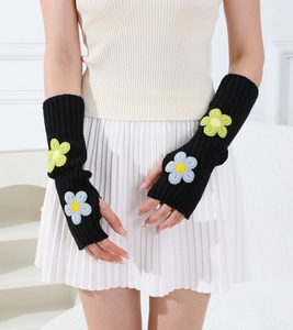 Macro shot of black knitted fingerless arm warmers with cute floral embroidery patches