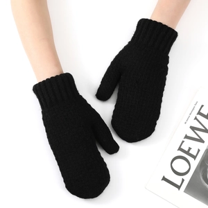 Close-up of thick knitted winter mittens with long ribbed cuffs in black color