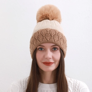 Dettaglio del cappello in maglia invernale con pompon soffice e texture bicolore beige marrone