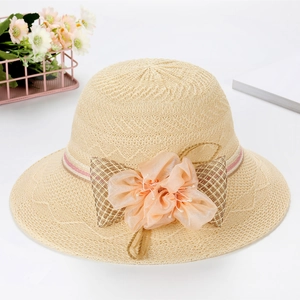 Detailed view of woven straw sun hat with pink organza flower and bow decoration