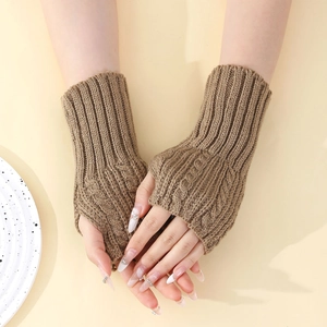 Détail des mitaines en tricot torsadé beige montrant la texture et les poignets