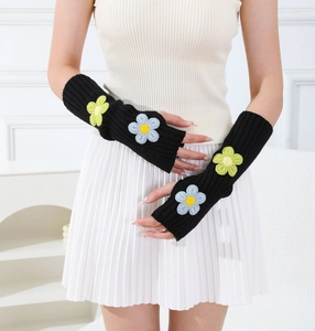 Detail of black rib-knit arm warmers with blue and green embroidered 3D flower accents