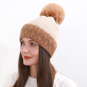 Dettaglio ravvicinato del cappello invernale in maglia beige a coste con tesa marrone