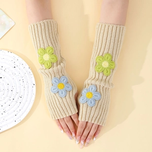 Close-up of beige knitted arm warmers featuring yellow and blue flower embroidery