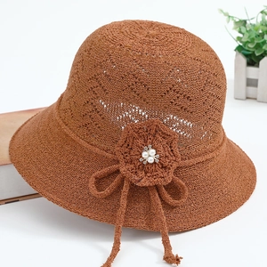 Detail of a brown crochet sun hat featuring handcrafted floral accents and white pearls