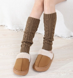Close-up of cable knit leg warmers in camel brown paired with plush slippers