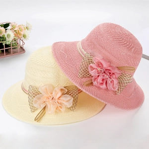 Detail of pink and beige woven sun hats with large floral accents and plaid bows