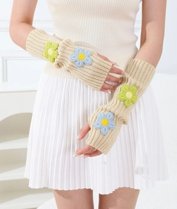 Close-up of beige knitted fingerless arm sleeves featuring 3D crochet flower details