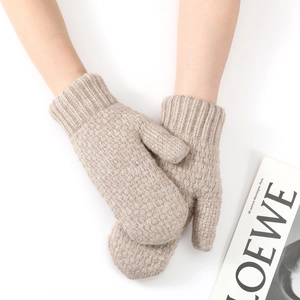 Detailed texture of thick knit winter mittens with ribbed cuffs in oatmeal beige color