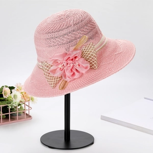 Detail view of a pink woven sun hat featuring exquisite silk flower and plaid ribbon bow