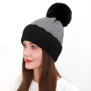 Dettaglio del berretto in maglia spessa con contrasto grigio e grande pompon nero