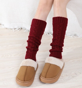 Close-up of cable knit leg warmers in dark red paired with plush platform slippers