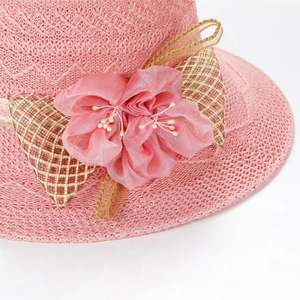 Detail of pink straw sun hat featuring a large chiffon flower and white bead accents