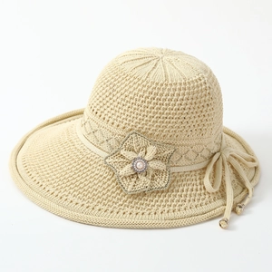 Detail of beige woven sun hat with floral embellishment and pearl accents for women