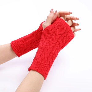Detail of red cable knit fingerless gloves showing rich texture and thumb hole design