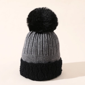 Dettaglio cappello invernale in maglia con pompon in ecopelliccia nera e trame grigie