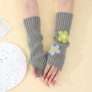 Detail of grey knitted arm warmers with floral embroidery and thumb hole design
