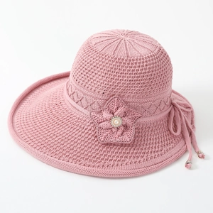 Detailed view of pink knitted sun hat with floral embellishments and pearl beads