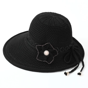 Detail of black sun hat with knit texture, side flower and white pearl decoration