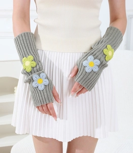 Detail of grey knitted fingerless gloves with colorful embroidered floral patterns