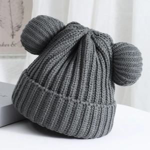 Detailed view of dark grey chunky knit beanie featuring cute oversized double pom-poms