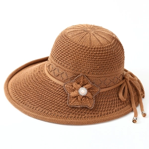 Close-up of woven sun hat with handcrafted flower, pearl accents, and golden metal tips