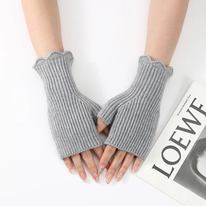 Close-up of light gray ribbed knit fingerless gloves with elegant ruffled wave cuffs