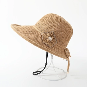 Detail of woven straw sun hat with floral pearl accents and adjustable chin strap