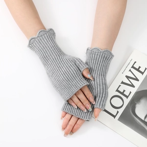 Detailed texture of light grey ribbed knit fingerless gloves with ruffled wave edges
