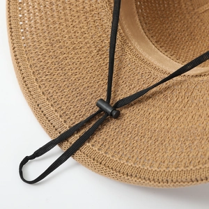 Close-up of khaki straw sun hat weaving with adjustable black chin strap and slider