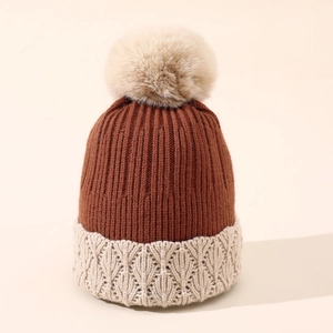 Trama dettagliata della maglia di un cappello invernale bicolore con pompon in ecopelliccia