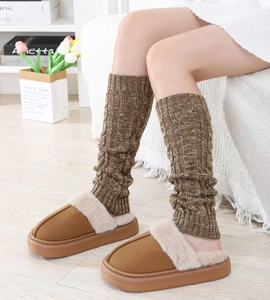 Detailed view of cable knit leg warmers paired with plush faux fur brown slippers