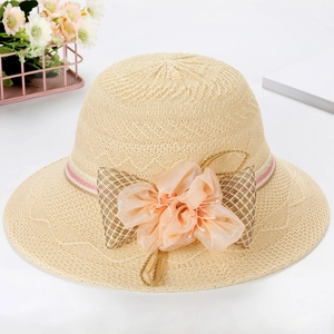 Women's summer straw sun hat with large floral decoration and pink bow on white background