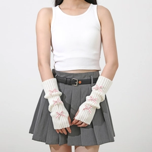 Close-up of white knitted arm warmer with pink bow details and thumb hole design