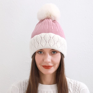 Dettaglio del berretto in maglia rosa e bianco con pompon e bordo all'uncinetto