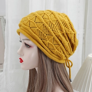 Dettaglio del berretto in maglia zenzero con motivo a rete e fiocco con coulisse
