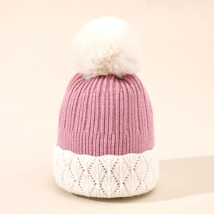 Dettaglio del cappello in maglia rosa e bianco con pompon e trama a foglia rifinita