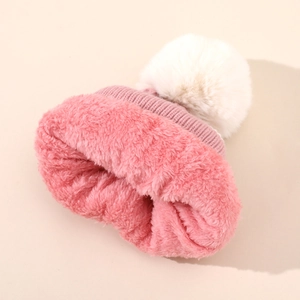 Dettaglio del cappello in maglia rosa con fodera in pile e pompon bianco morbido