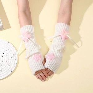 Detail view of white knit arm warmers with plush pink stars and delicate satin bows