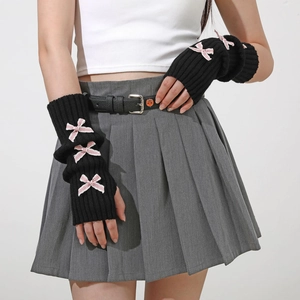 Detail of black ribbed knit arm warmers featuring three pink ribbon bows in Y2K style