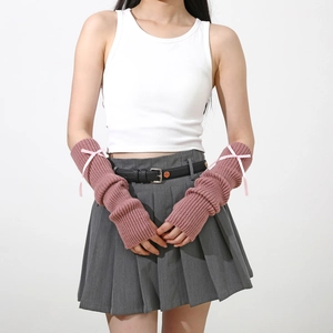 Détail de manchettes en tricot côtelé rose poudré avec de délicats nœuds en ruban rose