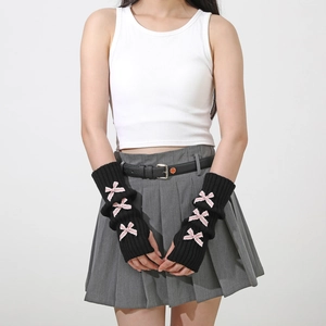 Close-up of black ribbed knit arm warmers featuring pink satin bow decorations