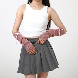 Détail de mitaines en tricot rose avec nœuds en satin blanc et texture à côtes