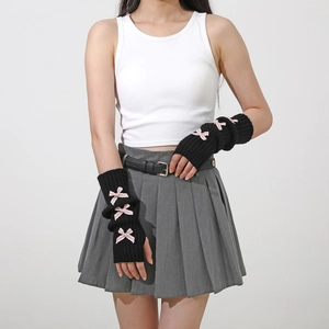 Detail of long black knit fingerless gloves with three small pink ribbon bows on the arm