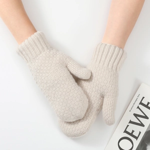 Detail of warm knit fingerless gloves in beige showing thick texture and ribbed cuffs