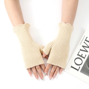 Detail of cream white cable knit fingerless gloves with elegant wavy ruffled edges