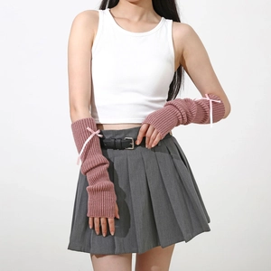 Détail de mitaines en tricot rose avec un nœud en ruban blanc au style Y2K