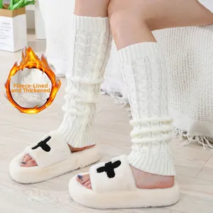 Λεπτομέρεια από πλεκτές γκέτες με επένδυση fleece και βελούδινες παντόφλες σε πάτωμα